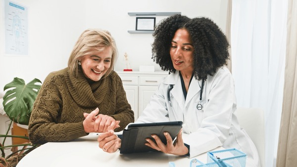 Doctor and patient having a friendly consultation while reviewing health information on a tablet